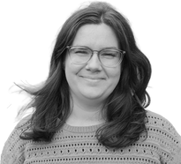friendly smiling photo of pool lift expert and company administrator, Martina Tsvetkova. She has long hair, blown slightly in the wind, glasses and a natural smile. Wearing aa knitted top. The photo is black and white.